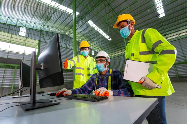 亚洲主管工程师与仓库工人协商重工业工厂内男性工业工程师在工厂的个人电脑上工作 — 图库照片