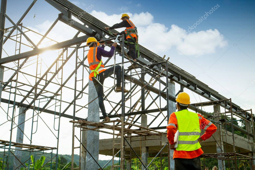Asian construction worker control in the construction of roof structures and worker wear safety height equipment to install the roof. Fall arrestor device for worker with hooks for safety body harness, Worker as in the construction sit