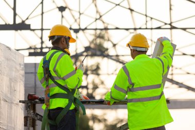 Asyalı mühendisler ve danışman işçiler, inşaat arka planında kullanılan tuğla miktarının çatının yapısı, inşaat ekibi çalışma kavramı olduğunu hesaplıyorlar..