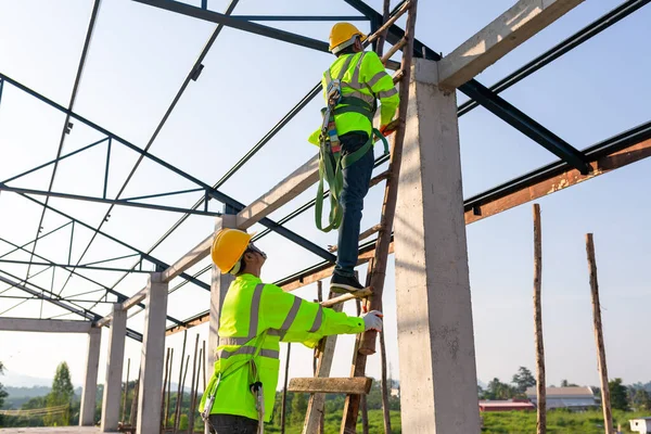 Safety height equipment in the construction site; Asian worker wear safety height equipment to install the roof. Fall arrestor device for worker with hooks for safety body harness.