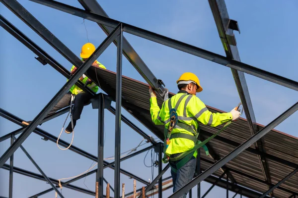 Asian roof construction worker wear safety height equipment to install the roof frame, Fall arrestor device for worker with hooks for safety body harness in the construction site.