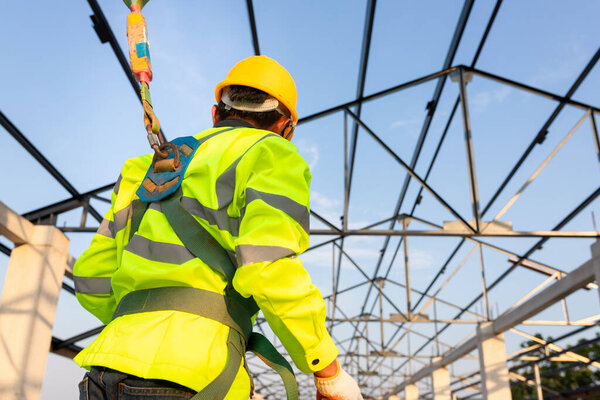 Safety height equipment in the construction site; Asian worker wear safety height equipment to install the roof. Fall arrestor device for worker with hooks for safety body harness.