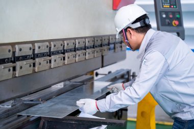 Endüstriyel fabrikada güvenlik kıyafeti ve levha bükme levhası giyen Asyalı teknisyen, ilk konsept güvenlik..