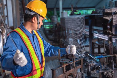 Endüstriyel fabrikada inşaat işleri için kontak üretim makinesi çelik tel örgüsünde çalışan Asyalı teknisyen.