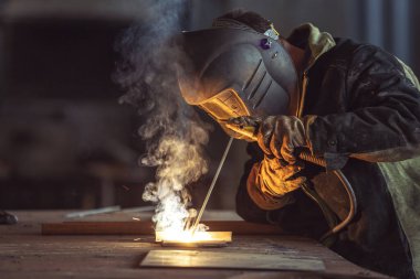 İnşaat alanındaki çelik kaynak fabrikasında güvenlik maskesi ve güvenlik eldiveni takan endüstri işçisi inşaat endüstrisi konseptinde güvenlik.