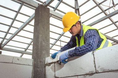 Otoklavlı beton bloklarla çalışan tuğla ustası. İnşaat alanına duvar örme, tuğla yerleştirme
