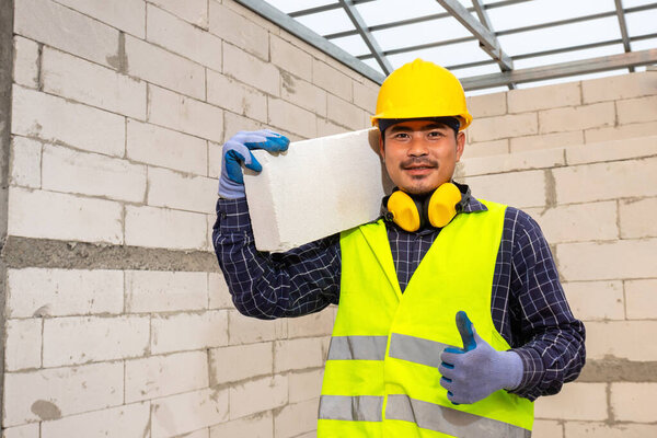 Worker reassure holds autoclaved aerated bricks in construction site, Concept proposes to use autoclaved aerated bricks in construction of houses.
