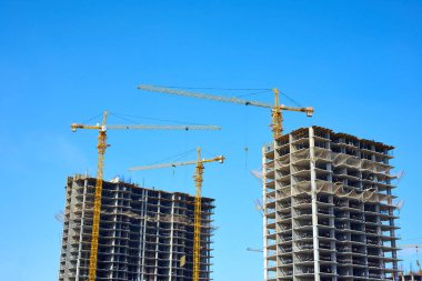 Bina ve vinçler yapım aşamasında. Yüksek katlı bina inşaat altında. Apartman İnşaat ve vinçler mavi gökyüzü altında.