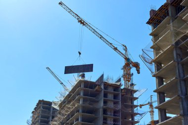Bina ve vinçler yapım aşamasında. Yüksek katlı bina inşaat altında. Apartman İnşaat ve vinçler mavi gökyüzü altında.