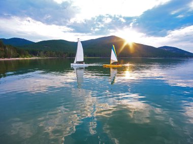 Imantau gölde gün batımında yelkenli katamaran tekneler. Yukarıdan görüntüleyin. Güzel gün batımı. Bulutlar suya yansıyan. Imantau Lake, Kazakistan.