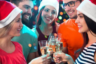 Mutlu bir grup genç arkadaş bardaklara dokunuyor.