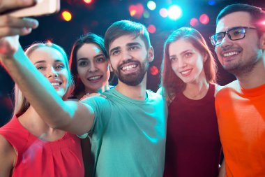 Bir grup mutlu arkadaş bir gece kulübünde selfie çekiyor.