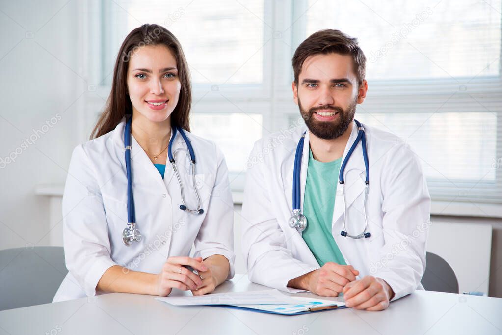 Group of doctors in clinic at workplace looking at camera and smiling