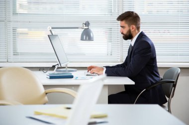 Ofiste bilgisayarla çalışan bir iş adamı