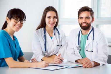 İş yerindeki klinikteki bir grup doktor kameraya bakıp gülümsüyor.