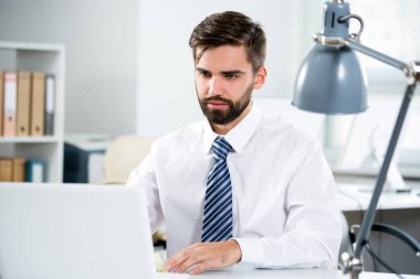 Ofiste dizüstü bilgisayarla çalışan bir iş adamı