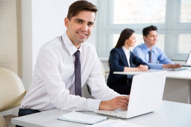 Young businessman in office smiling looking at camera clipart