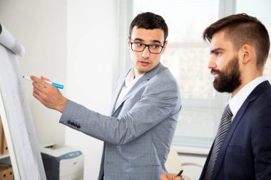 Ofiste beyaz tahtayla çalışan iş adamları.