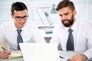 Ofiste dizüstü bilgisayarla çalışan iş adamları