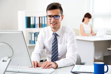 Young businessman in office smiling looking at camera clipart