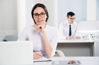 Ofiste gülümseyen genç ve çekici bir kadının portresi.