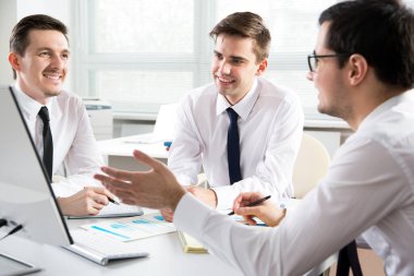 Ofiste yeni bir projede birlikte çalışan üç işadamı.