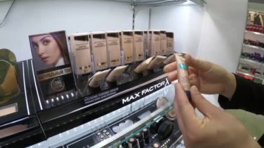 Minsk, Beyaz Rusya, 2 Haziran 2018: Genç kadın kozmetik deposunda Max Factor seçer. Kadın makyaj tester kullanır.
