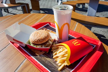 Minsk, Belarus - august 12, 2018: Tray with Big Mac hamburger menu on table on an open terrace in background of McDonald restaurant. clipart