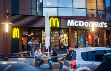 Minsk, Beyaz Rusya - 14 Mayıs 2018: akşam Mcdonalds restoranın önündeyiz insanlar açık terasta yemek yemek.