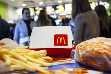 Minsk, Beyaz Rusya, 14 Nisan 2018: Büyük Mac kutu Mcdonald's logo, çizburger ve patates kızartması bir tepsi Mcdonald's restoranda yemek siparişi, insanlar arka planı