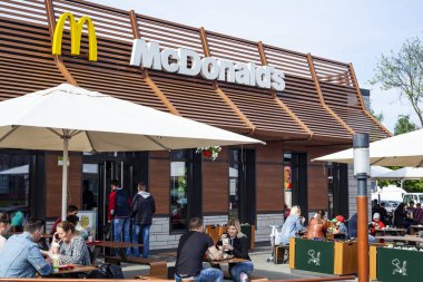 Minsk, Beyaz Rusya - 18 Mayıs 2017: Mcdonald's restoranın önündeyiz. Güneşli bir günde farklı yaştan insan yakındaki restoranın terasında masalarda yemek.