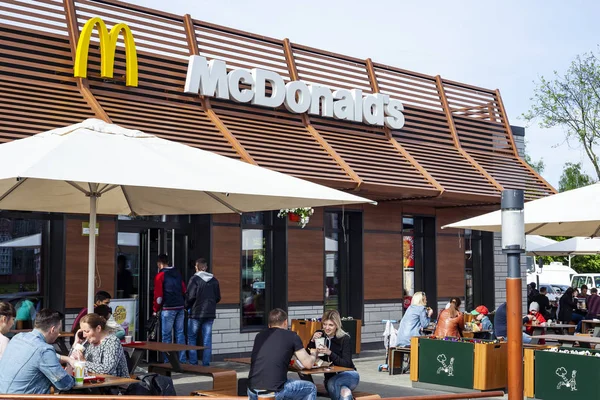 Minsk, Beyaz Rusya - 18 Mayıs 2017: Mcdonald's restoranın önündeyiz. Güneşli bir günde farklı yaştan insan yakındaki restoranın terasında masalarda yemek.