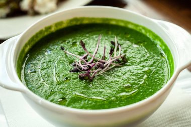 Bir kase içinde ıspanak püresi çorbası microgreens ile süslenmiş. Yakın çekim.