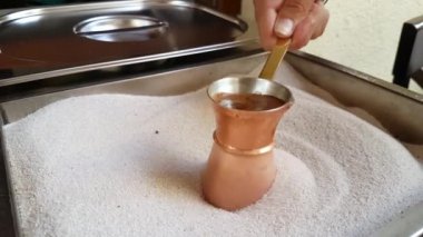 Sıcak kumlu kağıda hazırlanan bakır cezveden sıcak lezzetli, güçlü kahve.