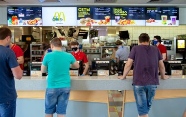 MINSK, BELARUS - 11 Haziran 2020: Tıbbi maskeli işçiler Coronavirus salgını sırasında McDonald 's restoranında müşterilere hizmet veriyor. Salgın sırasında yaşam biçimi.