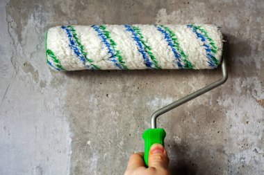 İnşaat işçisi duvarında paten fırçası olan bir astar kullanıyor. Kavram - yenileme.