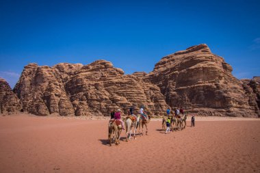 Çölde kayalık dağlarda yaşayan insanlarla dolu develer.