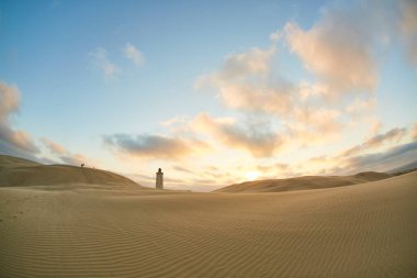 Sahilde gün batımında deniz feneri