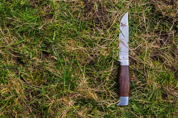 A vintage camping knife laying in the grass
