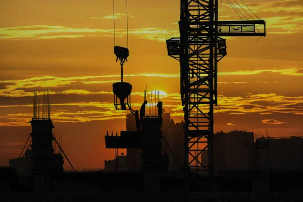 Silhouette of construction site & workers with sunset vibrant sky background