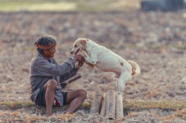 Phetchaburi Tayland: 9 Şubat 2019 Asya çiftçi bambu tüp için almak ile kuru çimlerin üzerine oturan şeker palm ve köpek, köpek dokunmadan elini koydu sahibi ile çok mutluluk