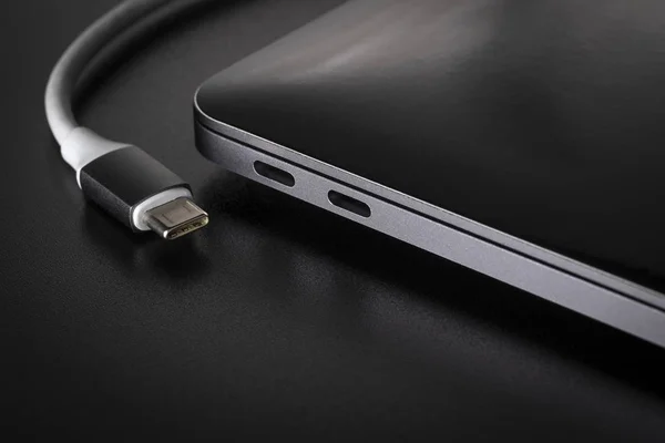 Dizüstü bilgisayar siyah arka plan üzerine bir Usb tip C kablo bağlantısı kesildi