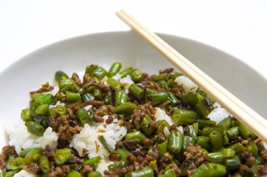 Kase kıyılmış sığır eti güveç ile yuvarlak fasulye haşlanmış pirinç üzerinde beyaz bir arka plan üzerinde yemek çubukları ile servis