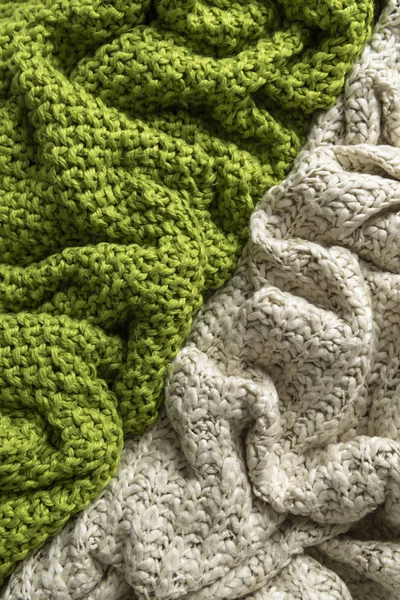 Wool blanket, white and green, knitted large chunky yarn. Close-up of knitted blanket on white background.