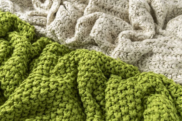 Wool blanket, white and green, knitted large chunky yarn. Close-up of knitted blanket on white background.