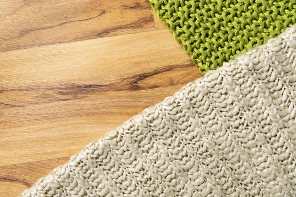 Wool blanket, white and green, knitted large chunky yarn. Close-up of knitted blankets on wooden background.