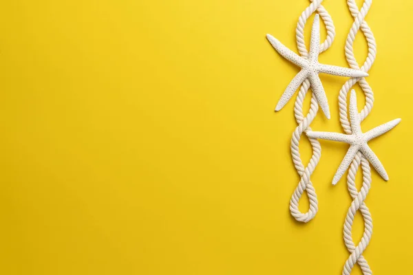 Summer time concept with starfish and rope on a plain yellow background