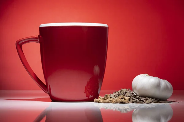 Çay ve izole kırmızı zemin üzerine sarımsak küçük yığını ile kırmızı kupa