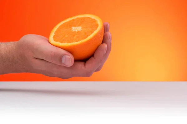 Sebuah Tangan Memegang Sepotong Jeruk Terisolasi Pada Latar Belakang Oranye — Stok Foto