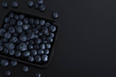 Siyah arka plan üzerine izole bir tepsi üzerinde mavi çilek demet